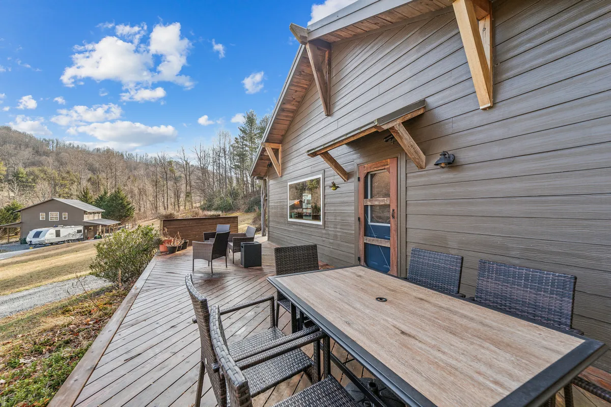 The deck is set for al fresco dining with a table and outdoor seating, while the background reveals a beautiful mountain view. The setup hints at memorable meals and gatherings, echoing the section's focus on grill nights, outdoor dining, and enjoying the surrounding nature.