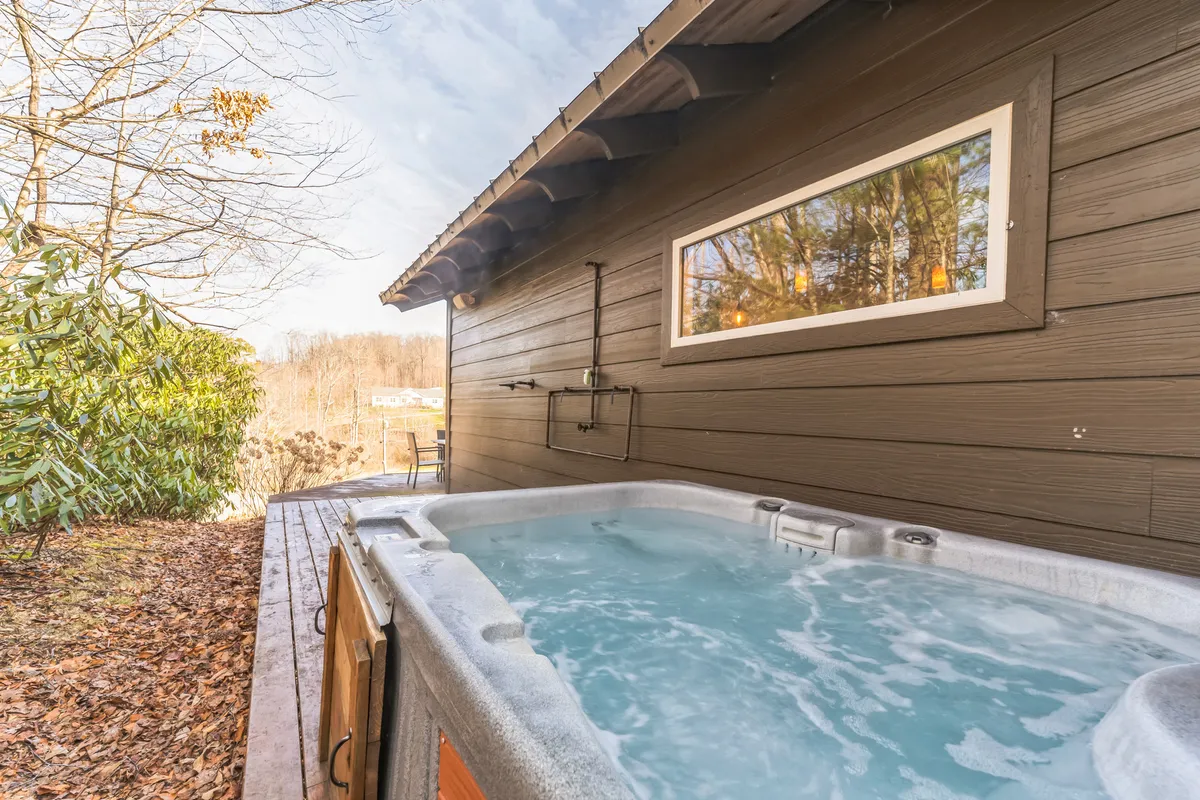 This image captures a wooden deck featuring a hot tub surrounded by lush greenery. The setting is tranquil, blending the comforts of relaxation with direct engagement with nature, and offers a hint of the adventure that awaits just beyond the property.
