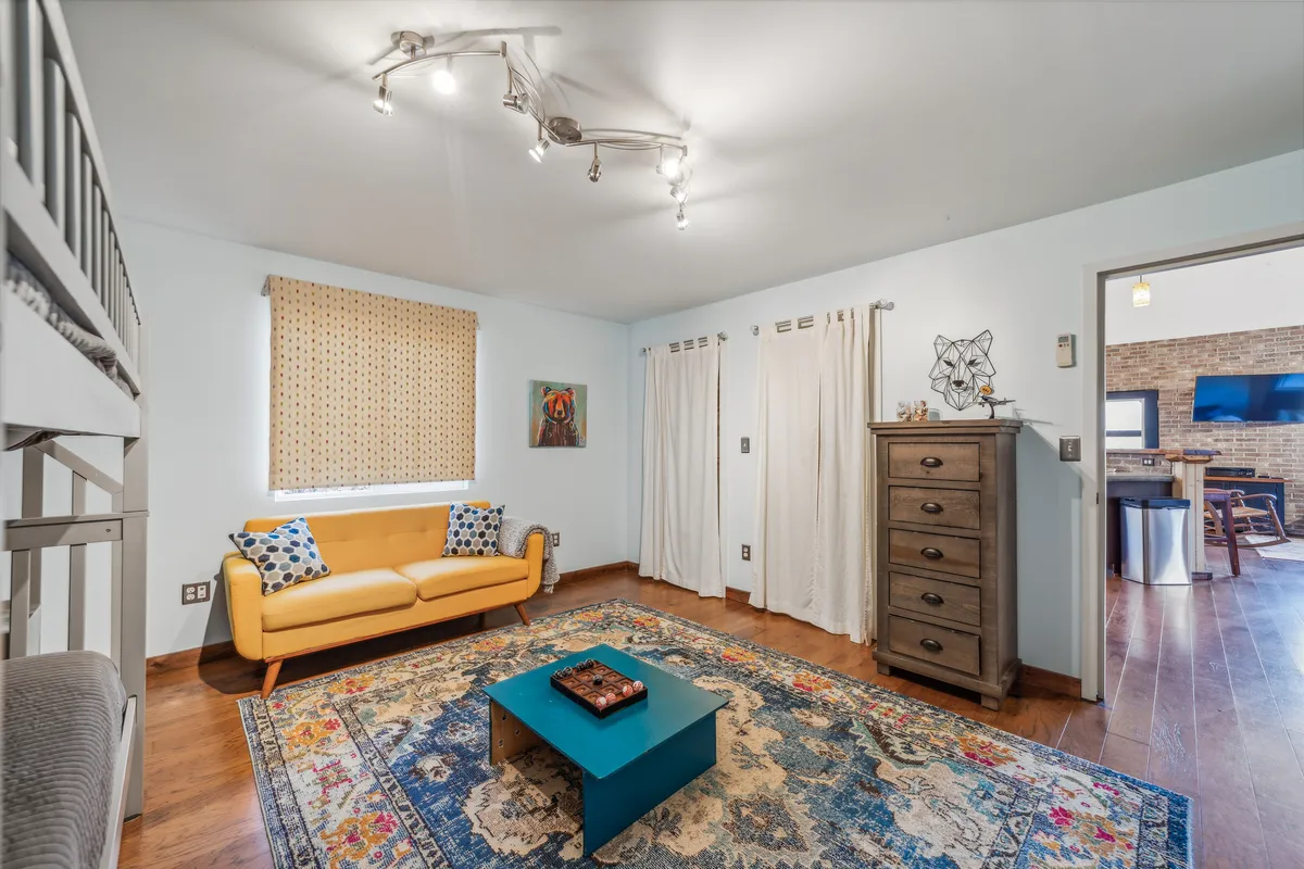 A welcoming seating area with a yellow sofa, colorful rug, blue coffee table, and striking wall art. The arrangement conveys warmth, comfort, and personality, echoing the Airstream’s promise of a stylish and nostalgic atmosphere.