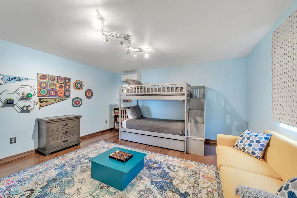 This image highlights a lively interior space featuring a bunk bed, colorful wall art, a blue coffee table, and a yellow couch. The playful decor and cozy setup create a fun, family-friendly vibe that fits perfectly with the sense of adventure and uniqueness the Airstream experience promises.